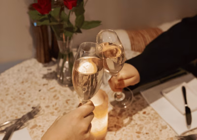 Proosende champagneglazen boven een Valentijnstafel met rozenblaadjes